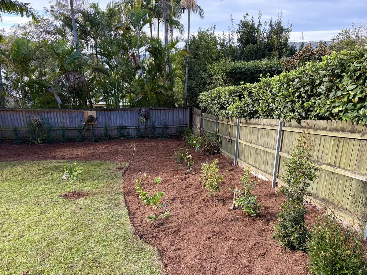 The same corner garden bed after mulching, with a clean curved edge to the lawn
