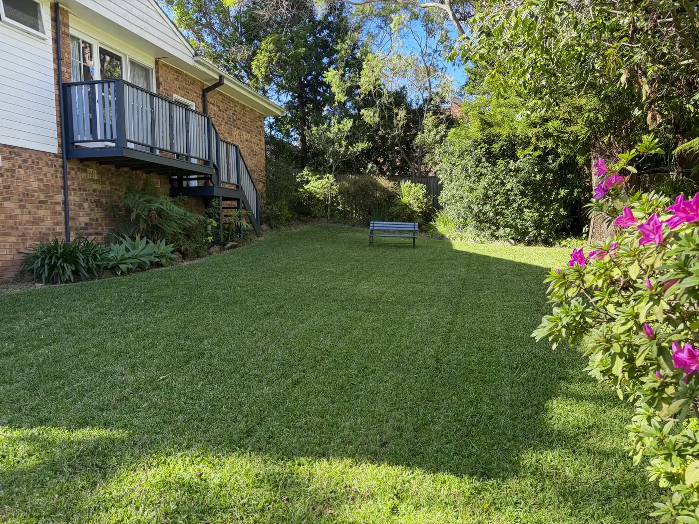 Freshly mown lawn with neat stripes beside a brick house and timber stairs